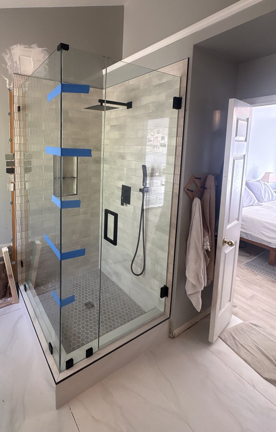 Frameless corner shower enclosure with matte black clamps