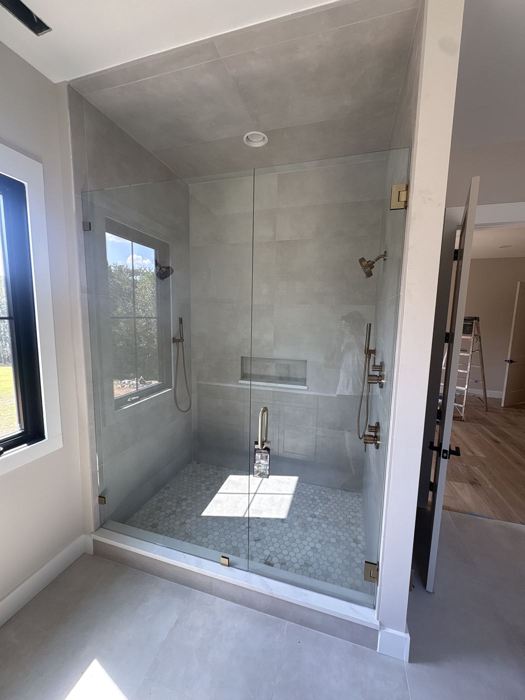 Frameless walk-in shower with door and fixed panel, brushed gold hardware