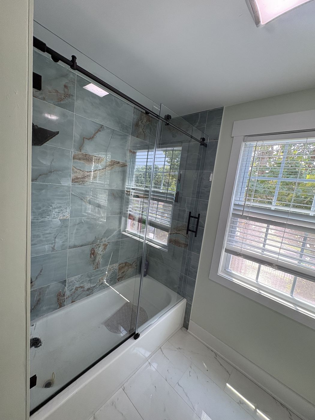 Frameless sliding tub door with dark bronze track