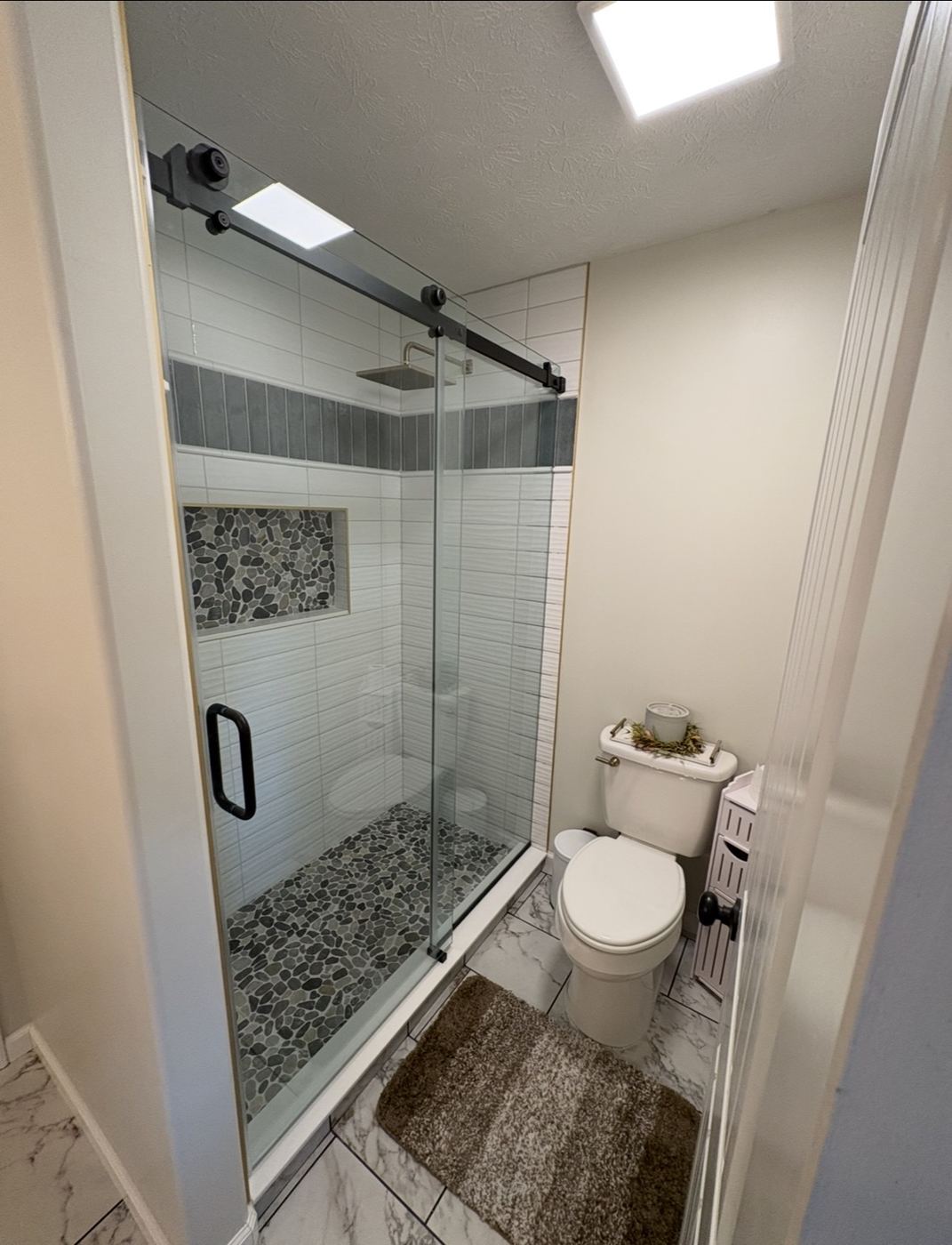 Frameless sliding shower door with matte black roller hardware