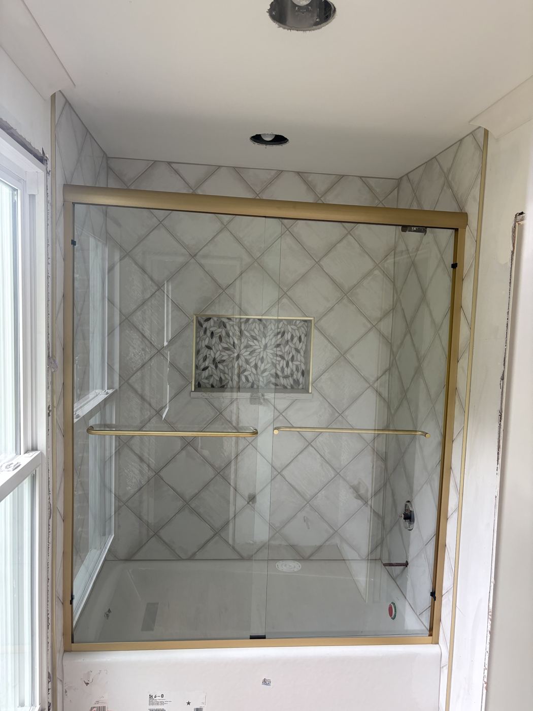 Brushed gold framed bypass doors over a tub