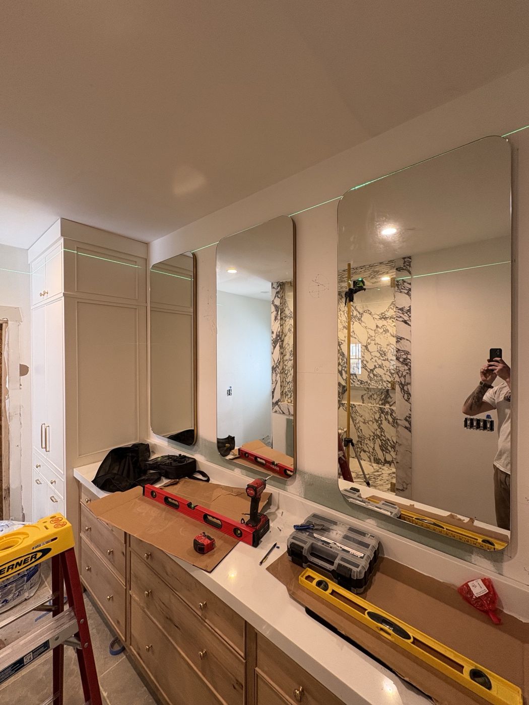 Three tall rounded-corner vanity mirrors laser-leveled over a double vanity