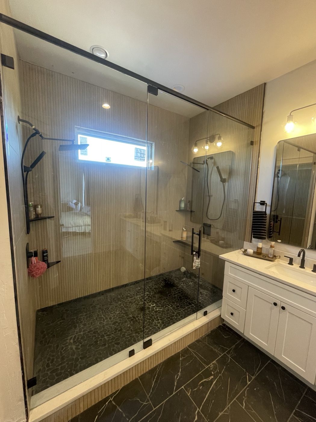 Large frameless walk-in shower with fixed panels, door and matte black header bar